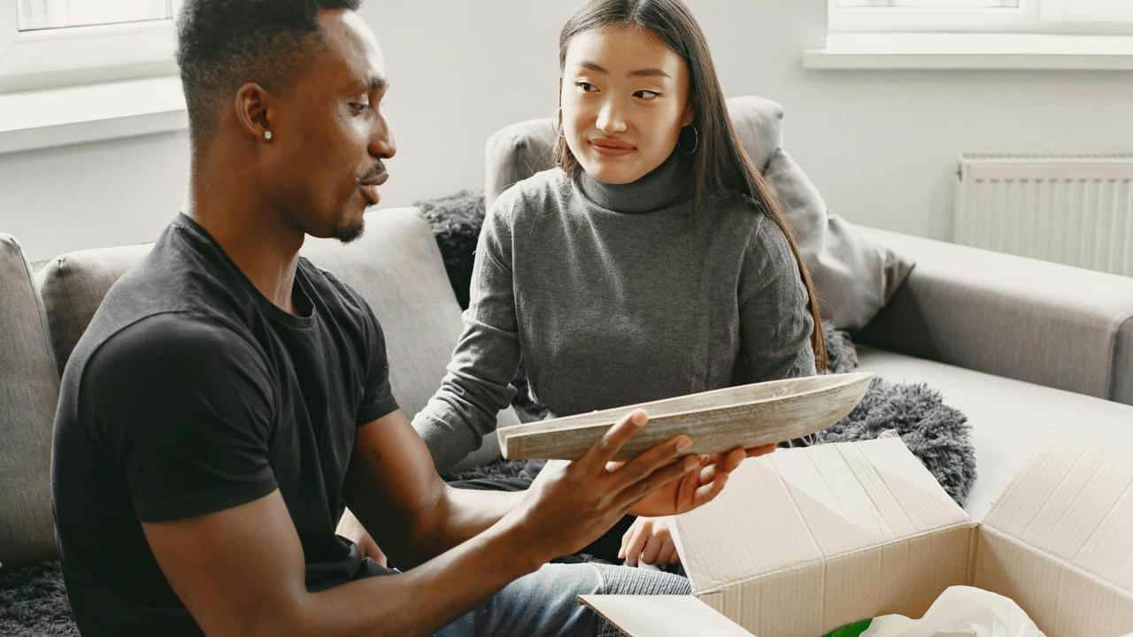 A man holding a framed item while sitting next to a woman on a couch.