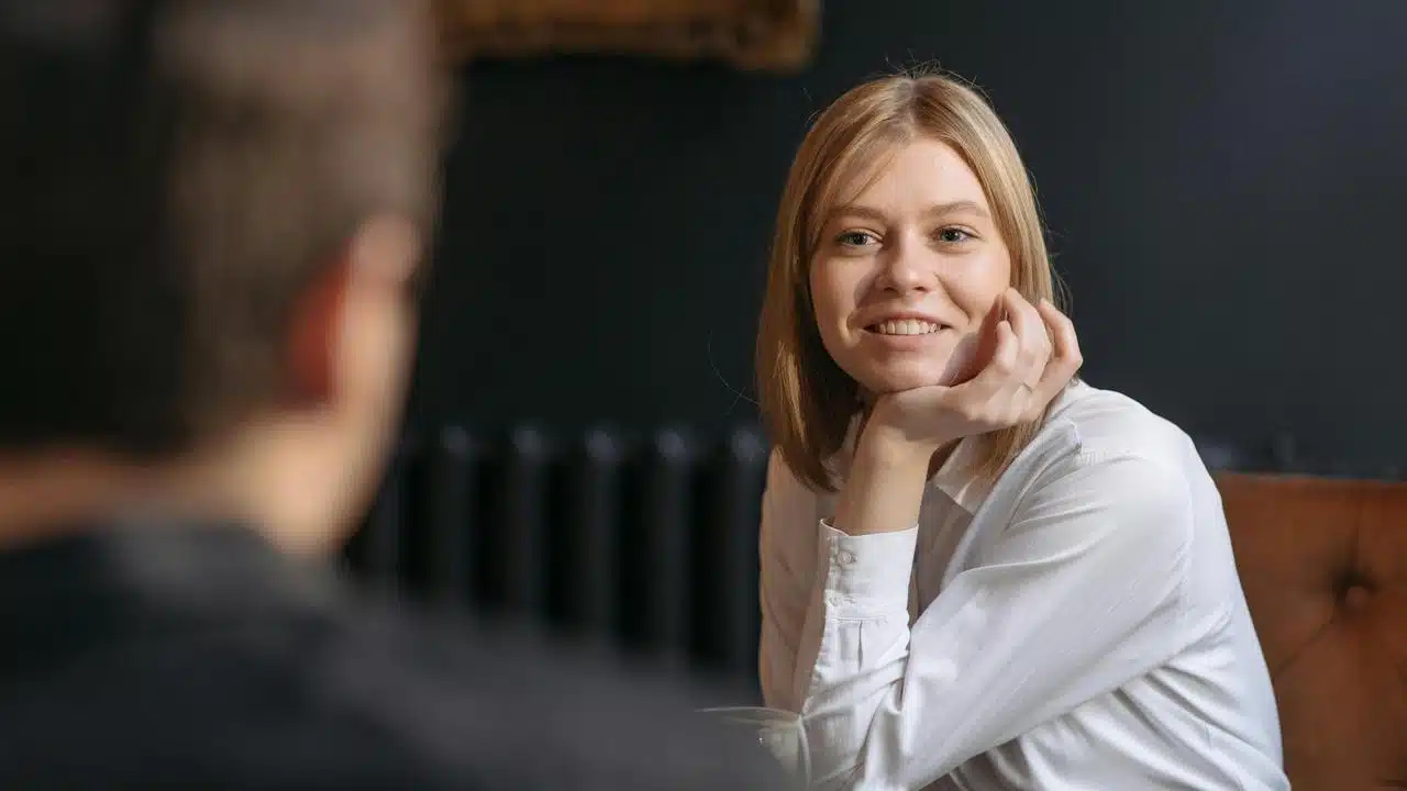 A woman smiling across a table during a conversation.