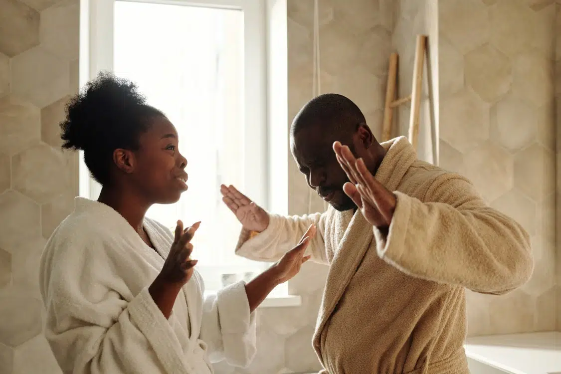 A couple wearing bathrobes having a word in the bathroom.