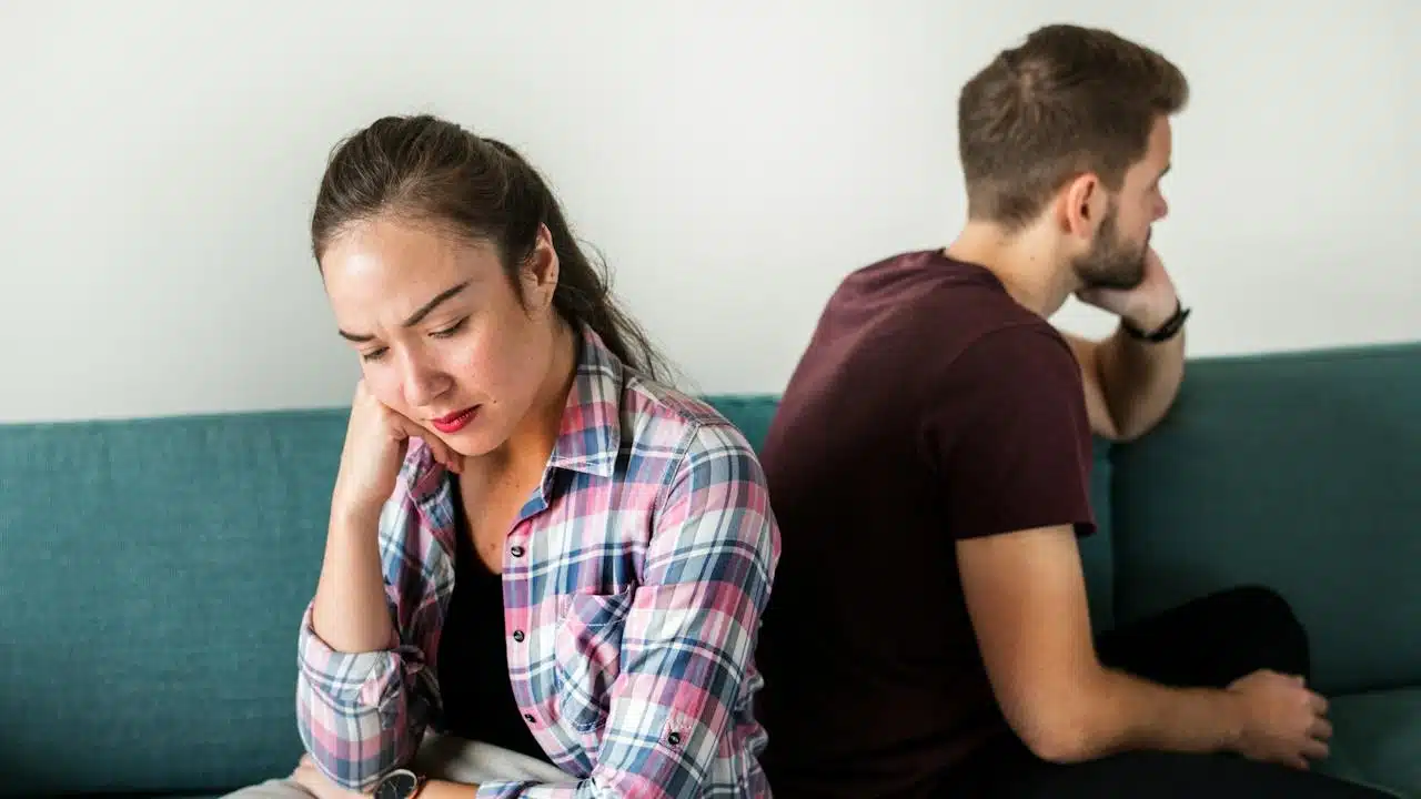 A couple sitting with their backs to each other and not talking.