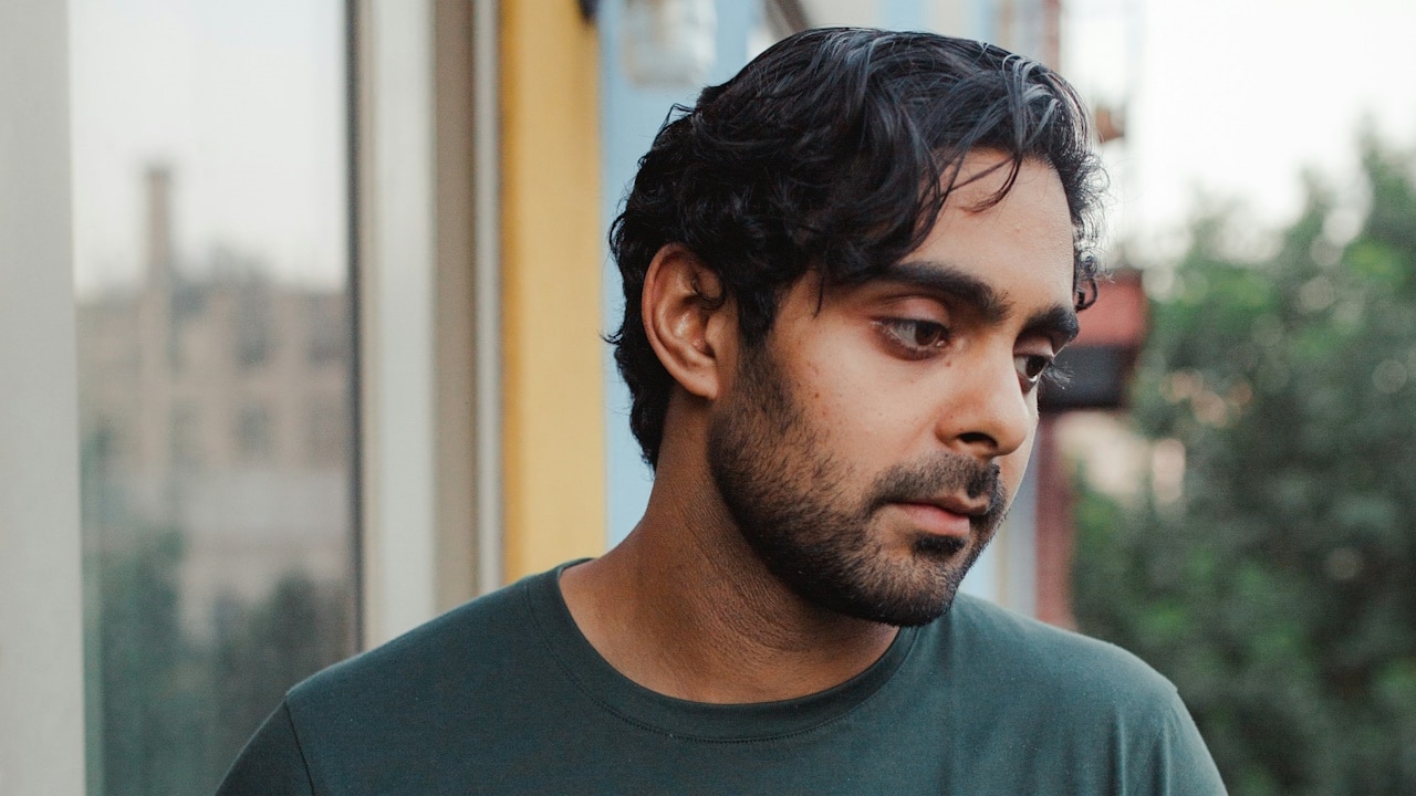 A lightly bearded man looking depressed.
