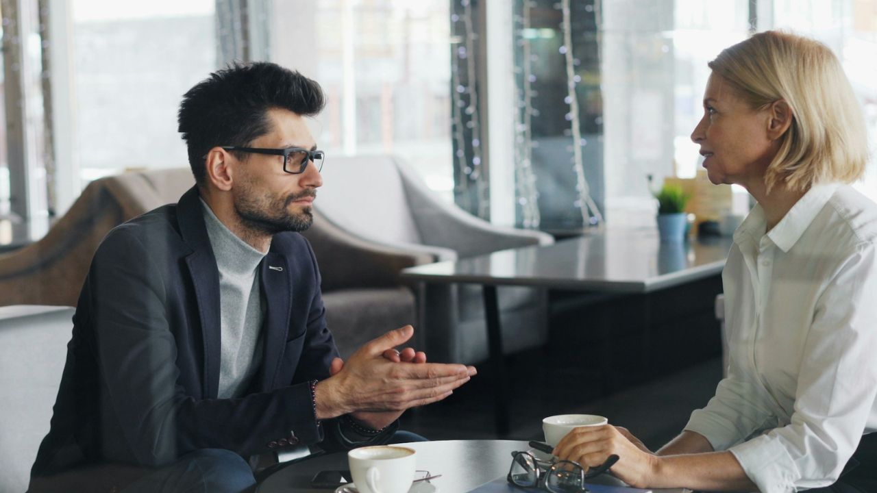 Couple sitting at a table having a serious conversation in a cafe.
