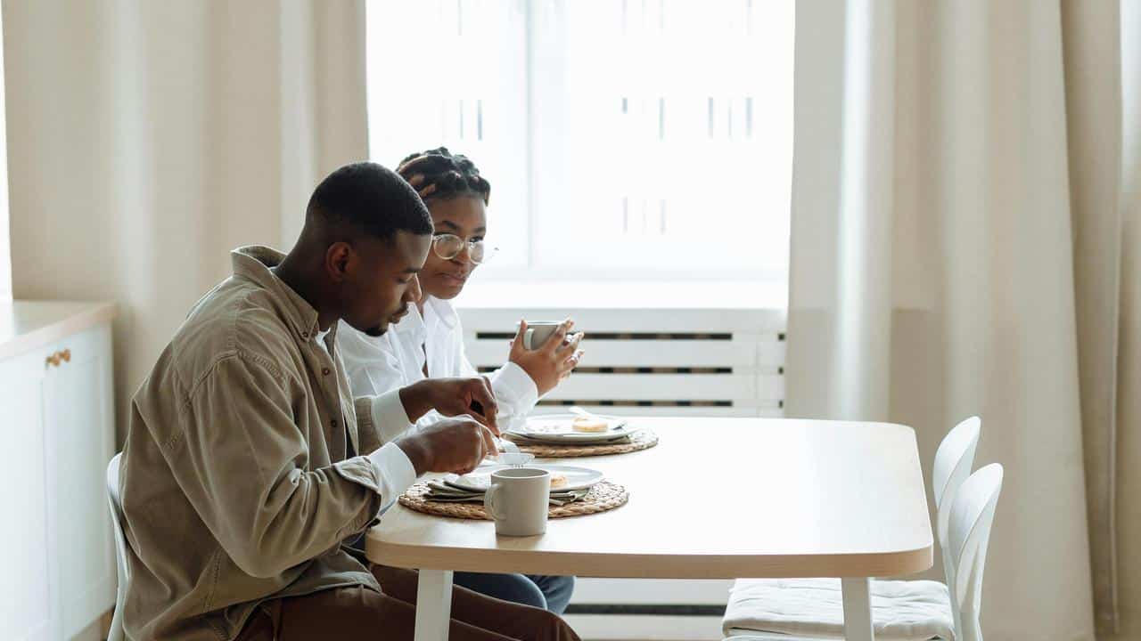 A couple eating breakfast together at a small kitchen table.