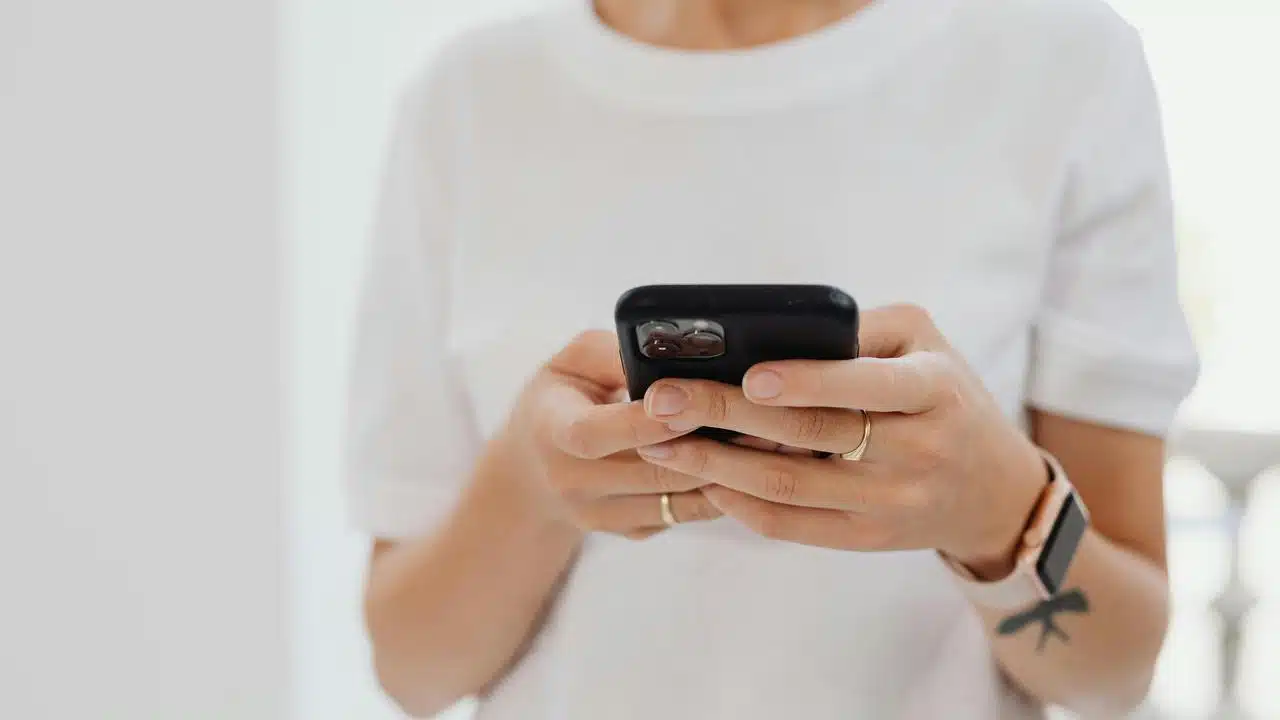 A person holding and using a smartphone with both hands.