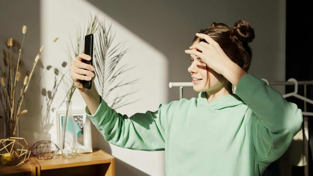 A person taking a selfie while adjusting their hair.