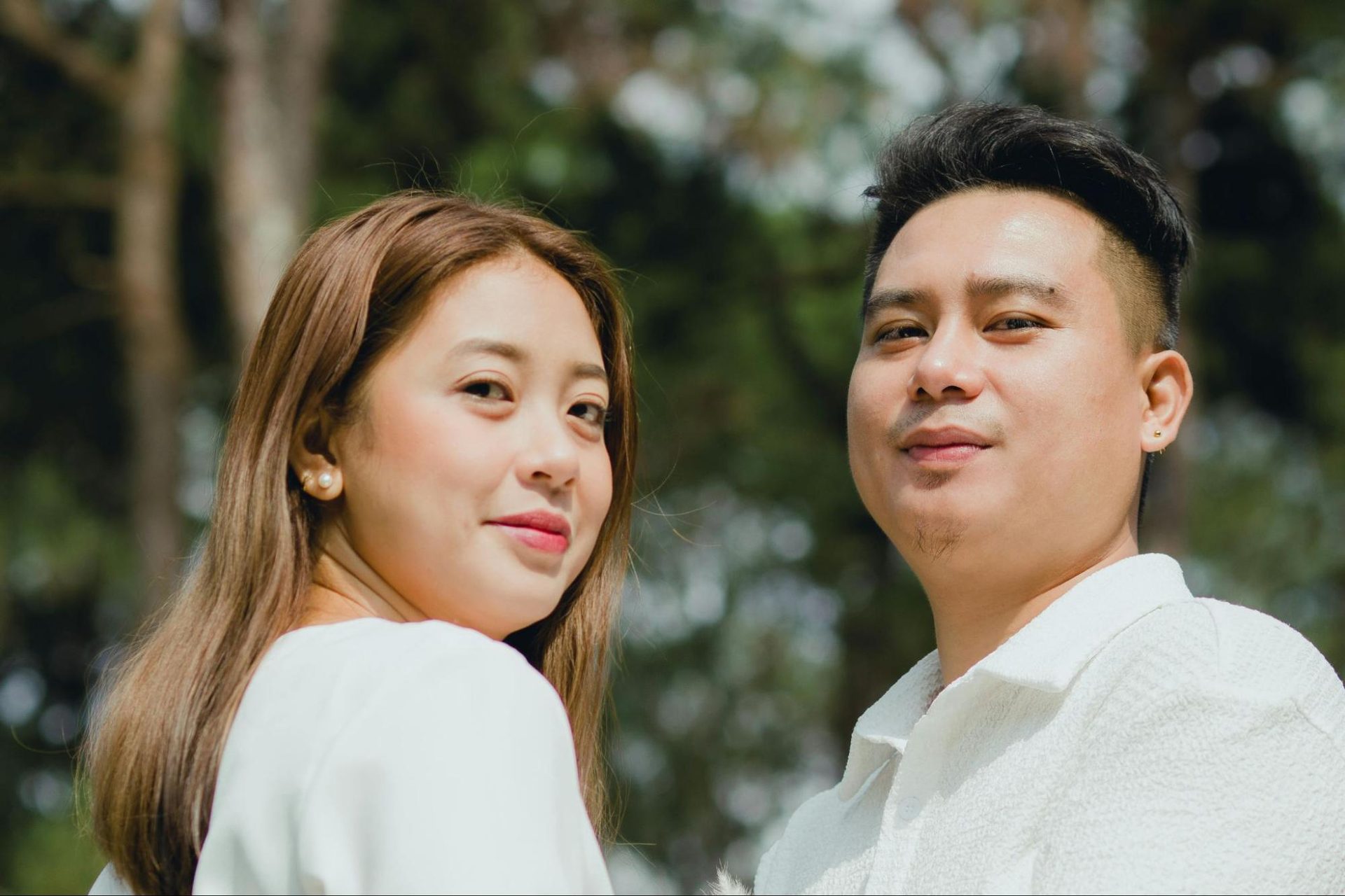 Woman smiling softly with relaxed posture while standing beside a man
