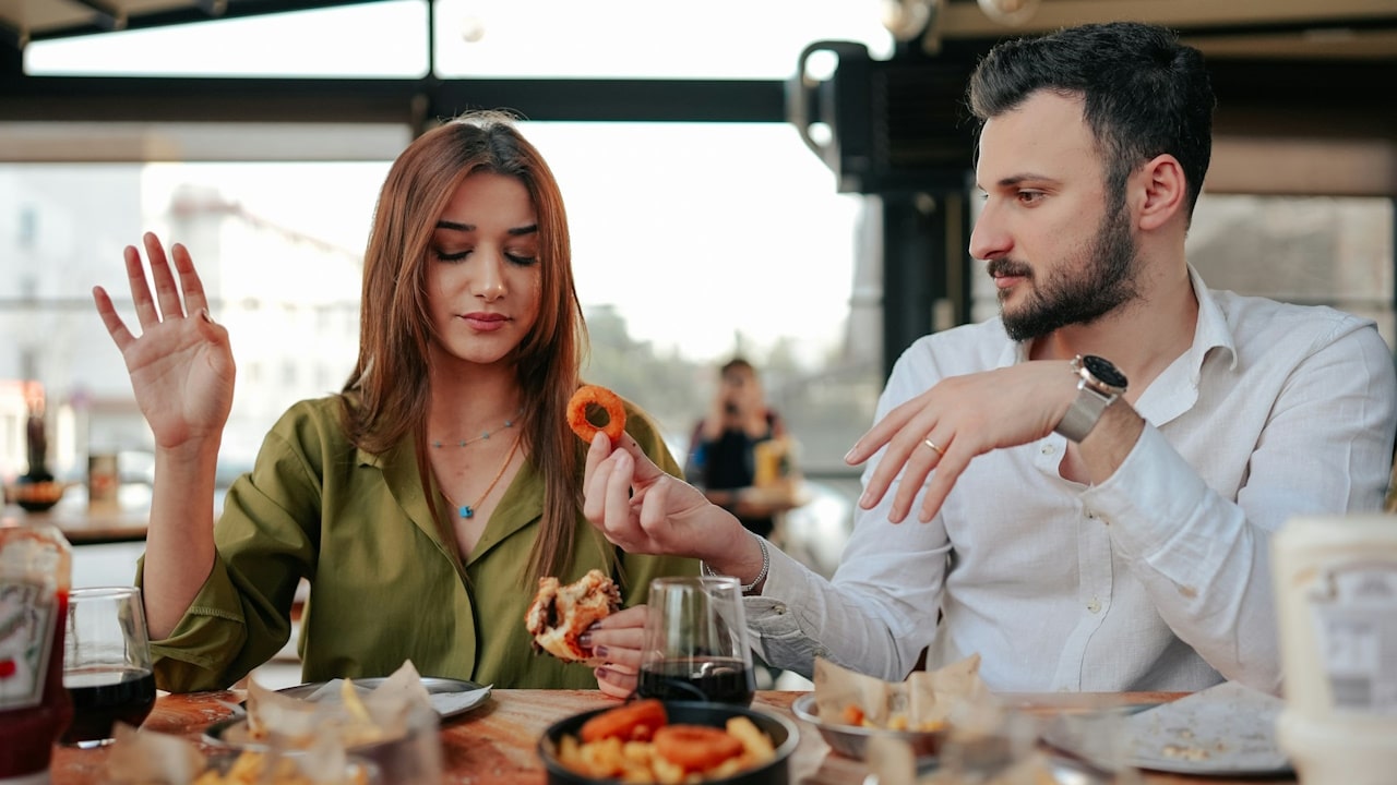 A man and a woman sitting at a table eating food.