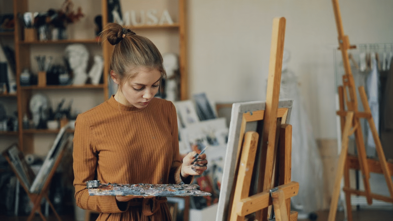 A young woman painting on a canvas.