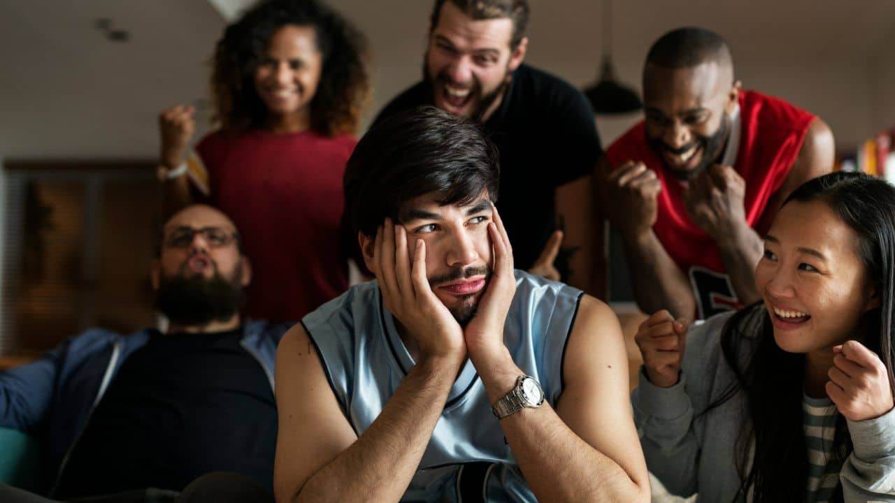 A man sits with his head in his hands while people cheer behind him.