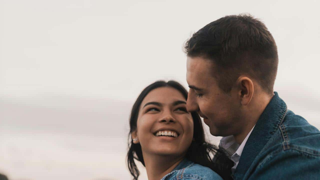 A smiling couple sharing a close moment outdoors.