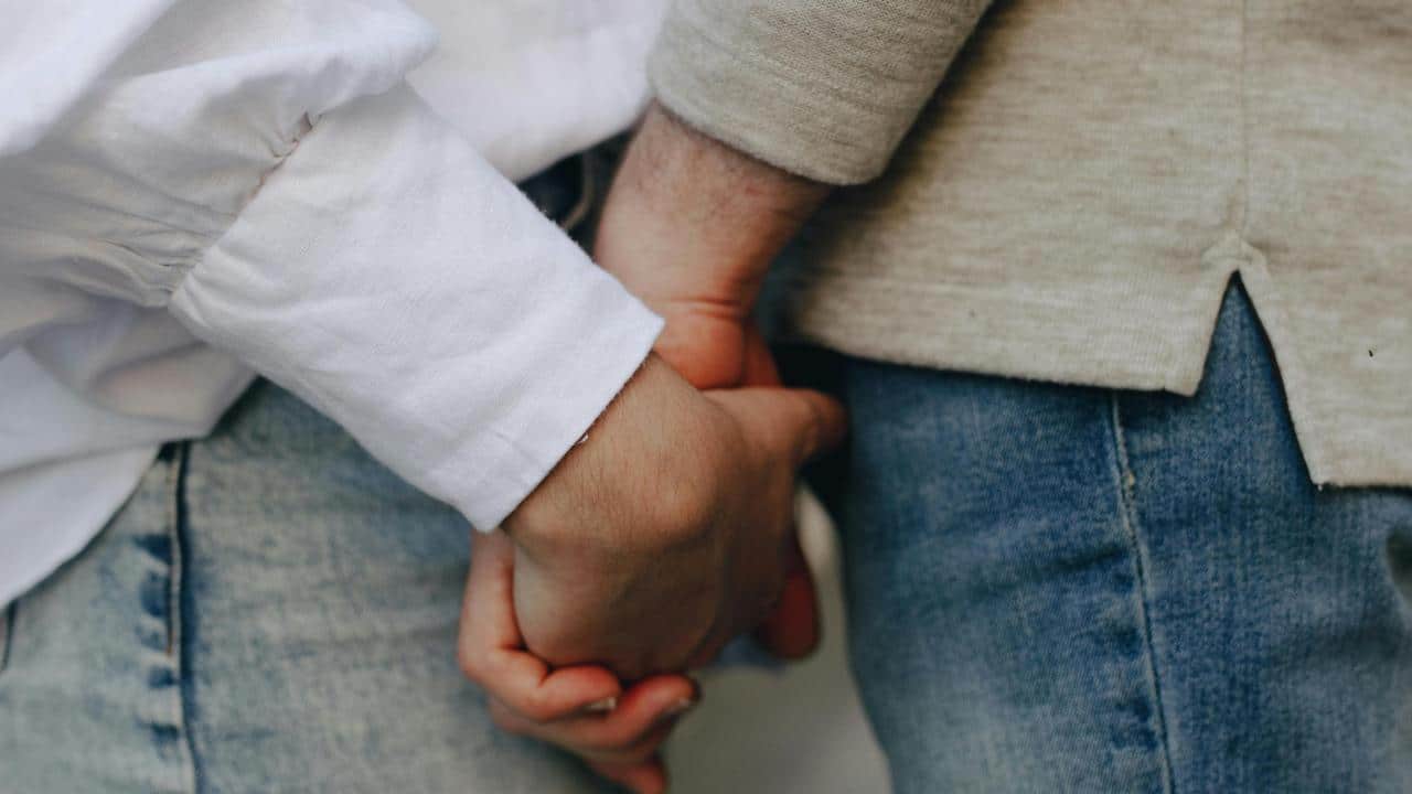 A close-up of two people holding hands.
