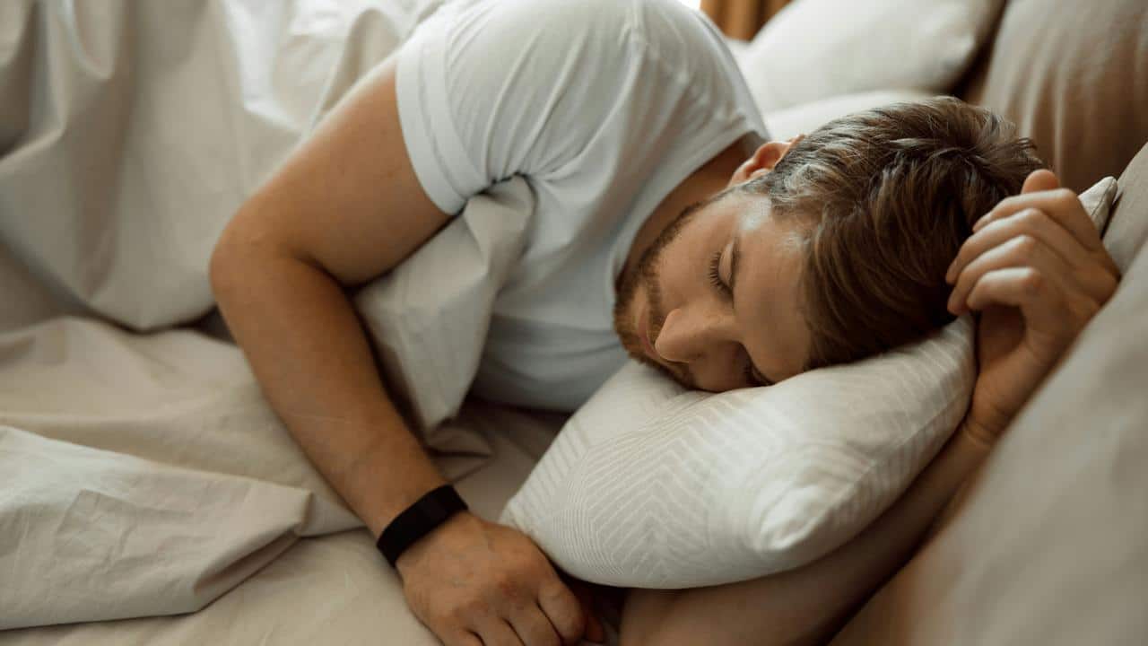 A man sleeps peacefully on his side with a pillow under his head.