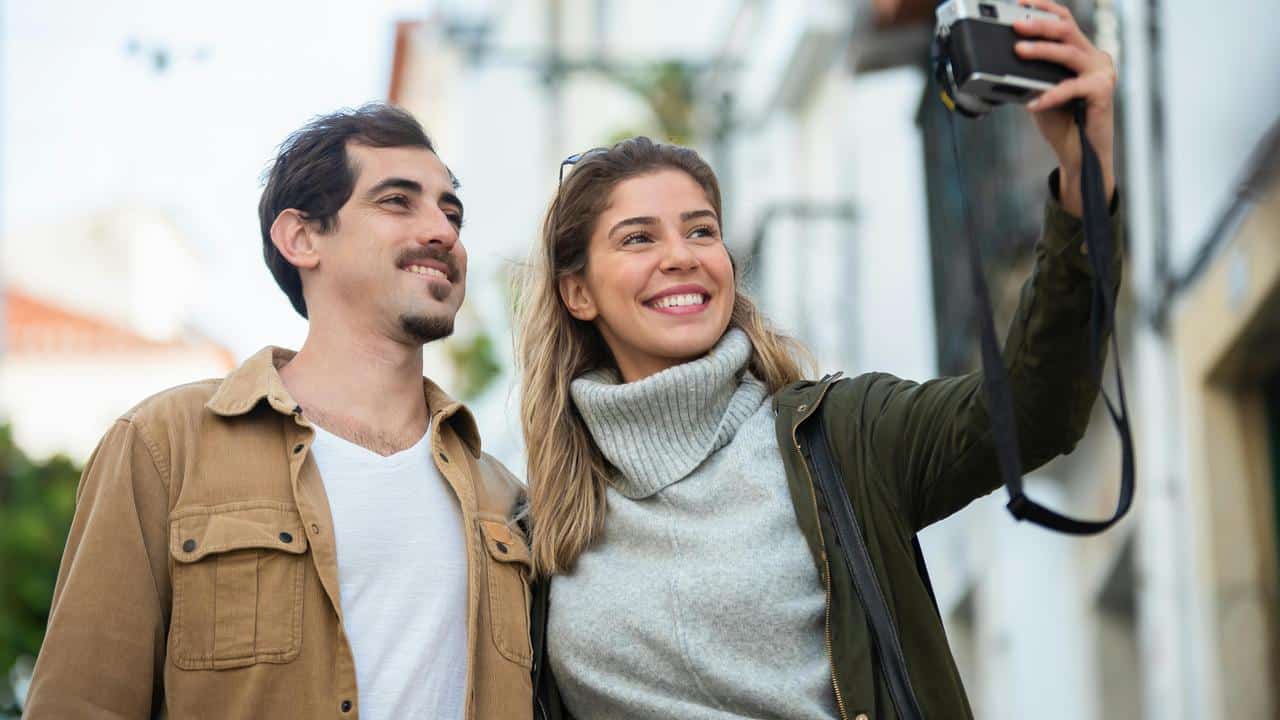A smiling couple taking a selfie outdoors.