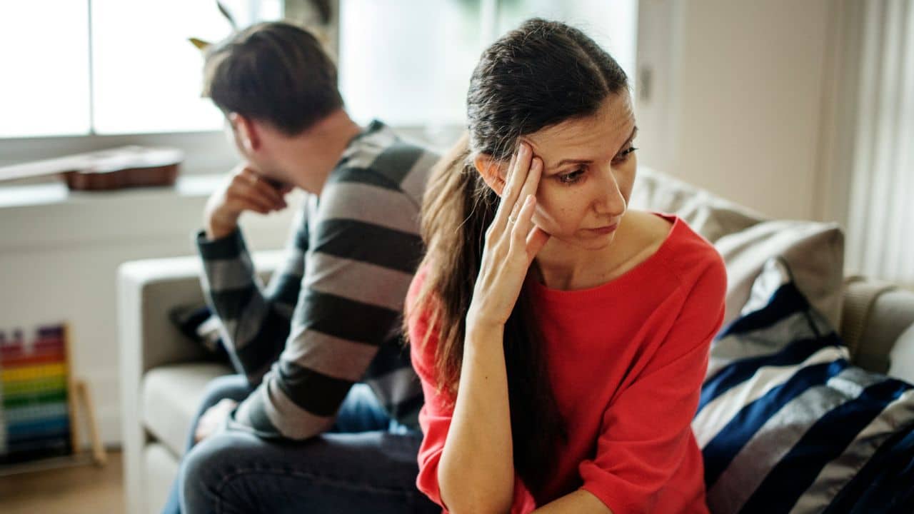 A woman rests her head on her hand while a man sits facing away behind her.