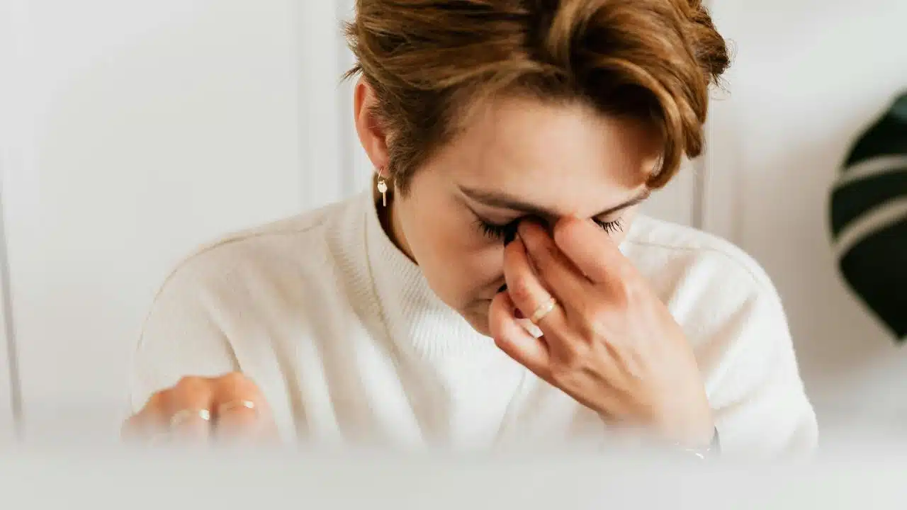 A woman rubbing her eyes, appearing tired or stressed.