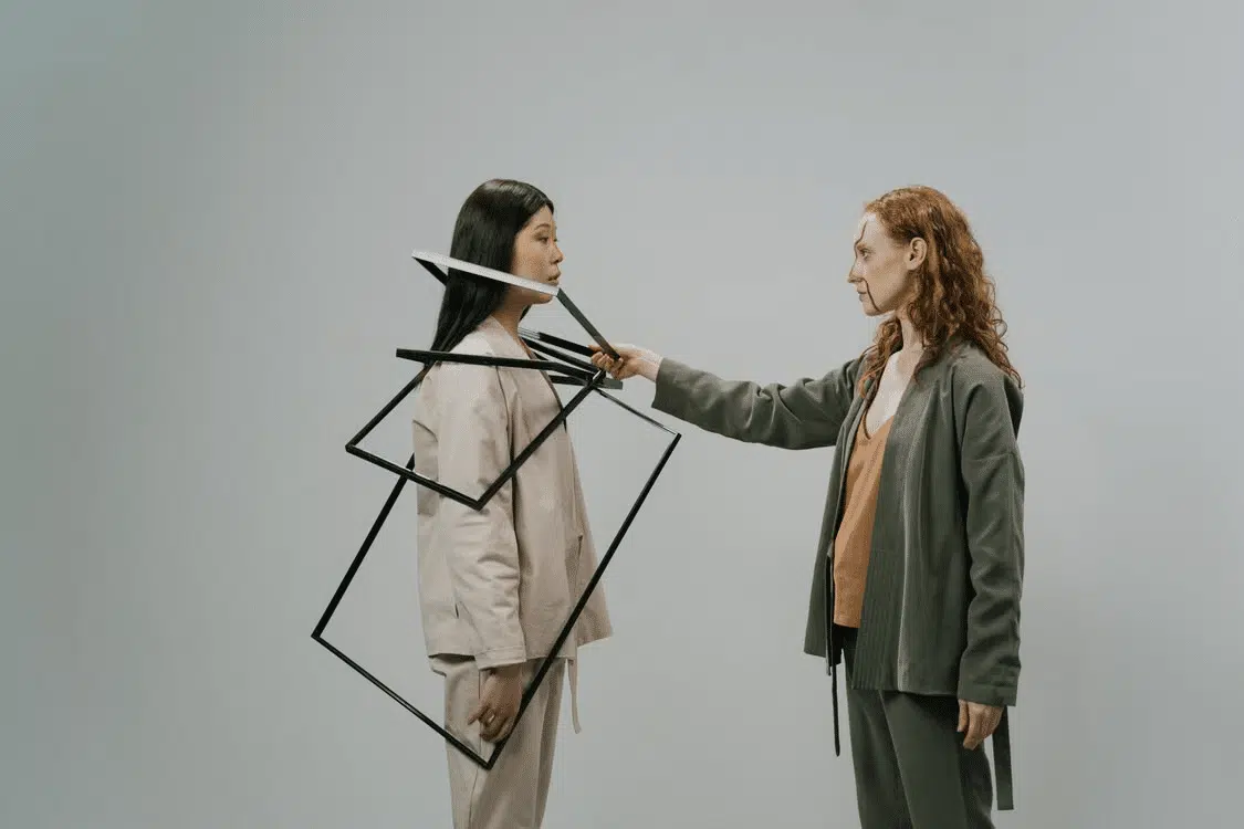 Two women posing for a photo as one frames the other.