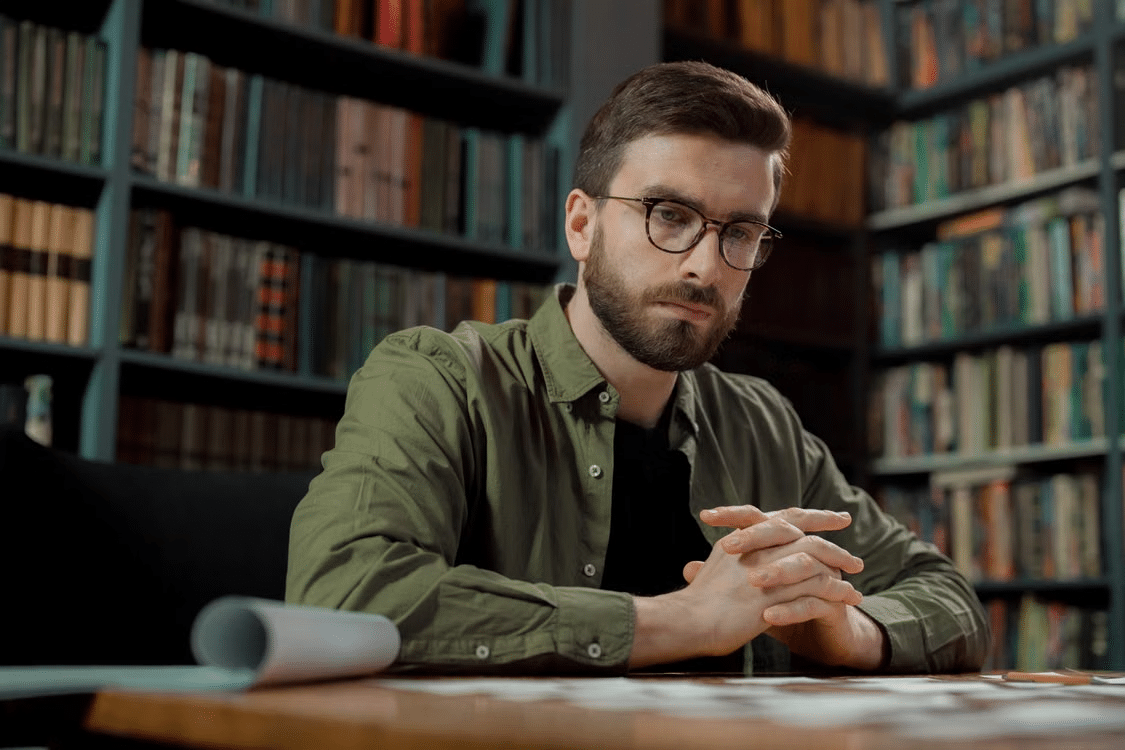 A man with glasses immersed in thoughts.