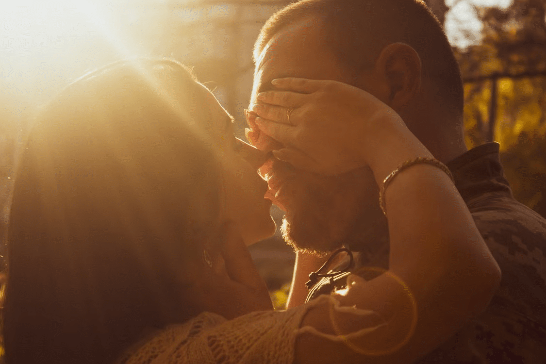 A woman showing her love for a woman as she covers his eyes to land a kiss.