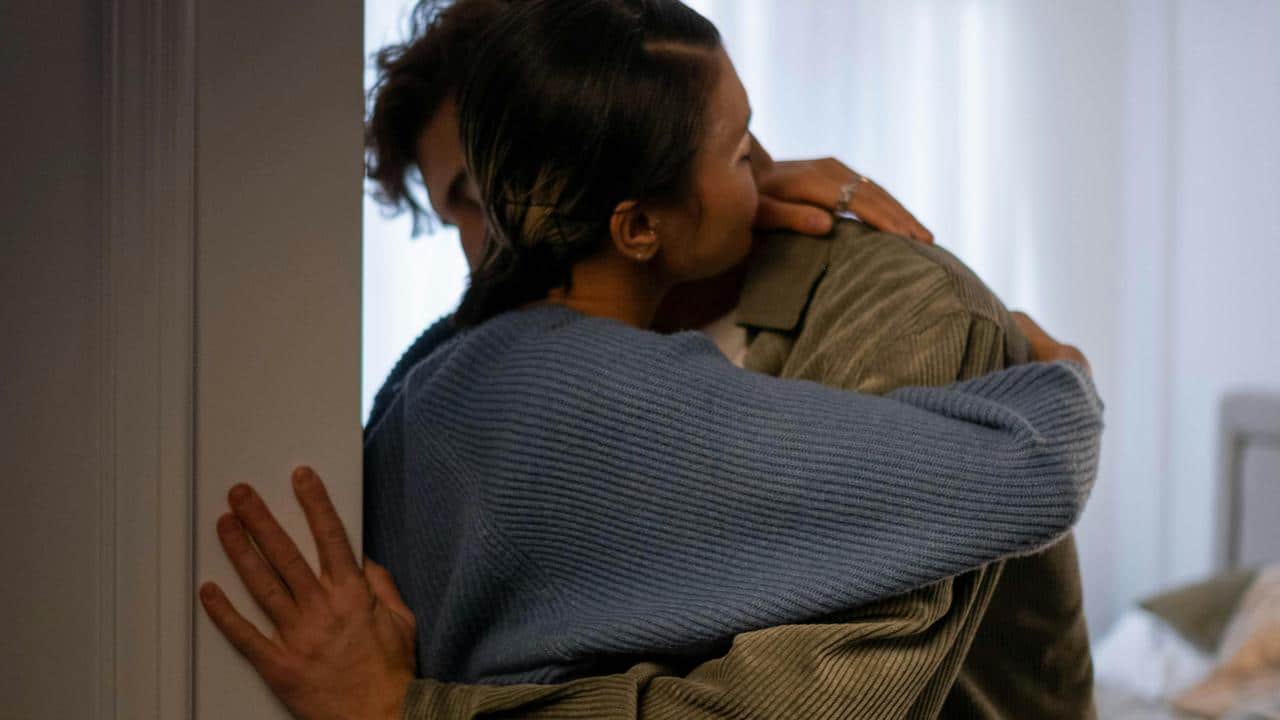 A couple embracing quietly in a doorway.