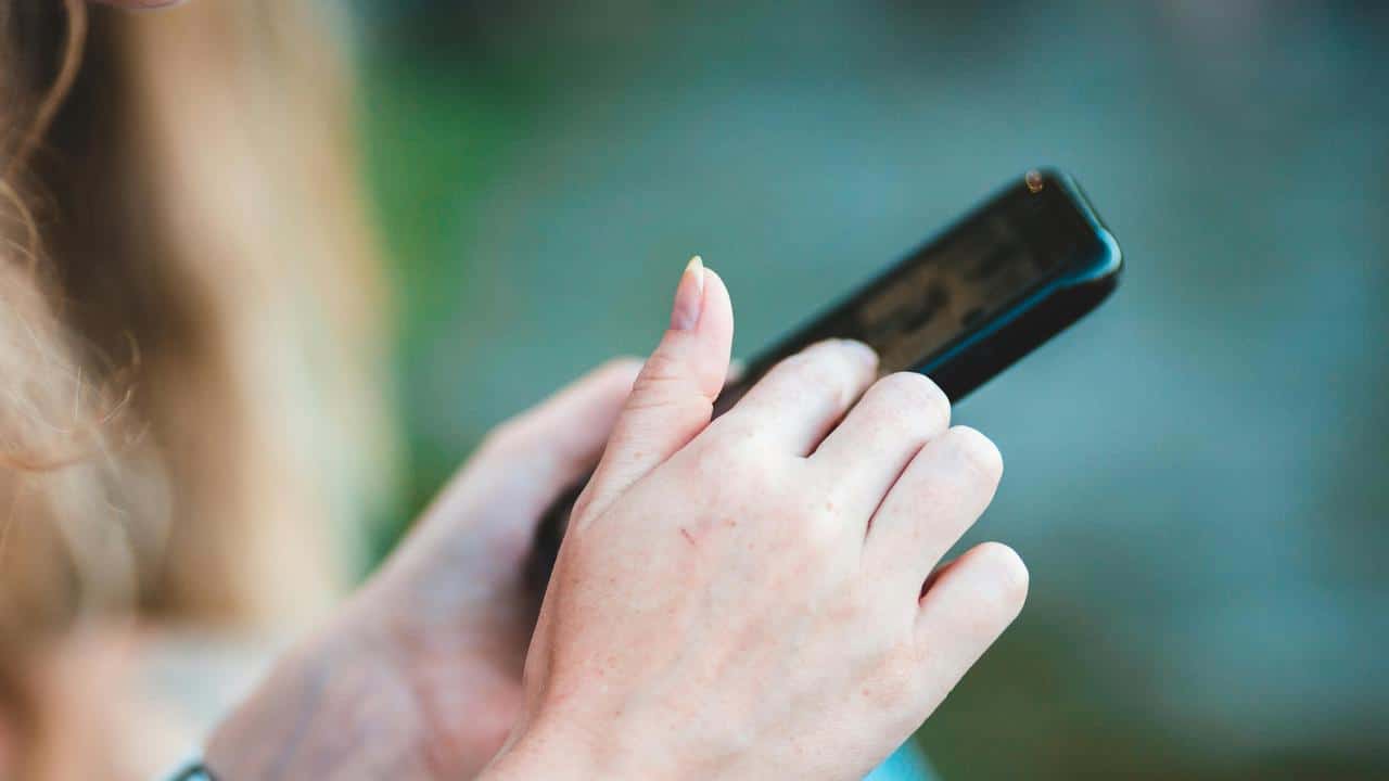 A close-up of a person using a smartphone outdoors.