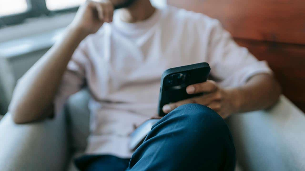A person sitting and looking at a smartphone.