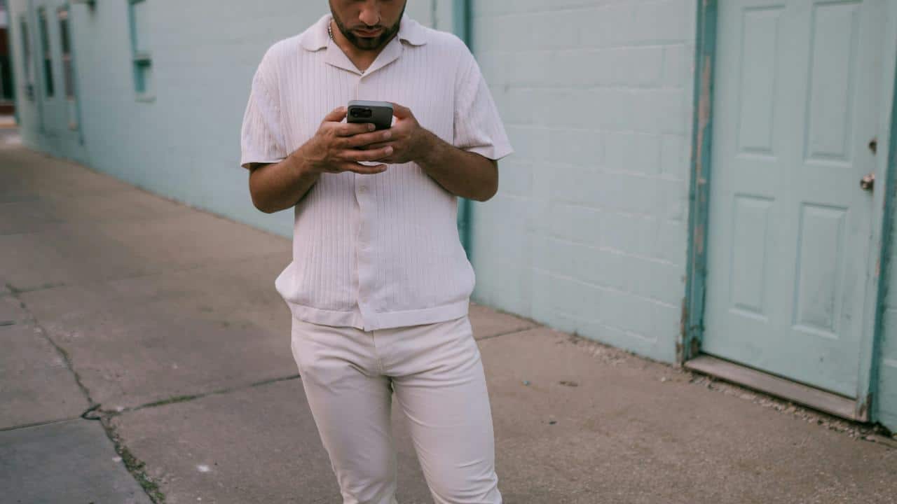 A person walking on a sidewalk while looking at their phone.