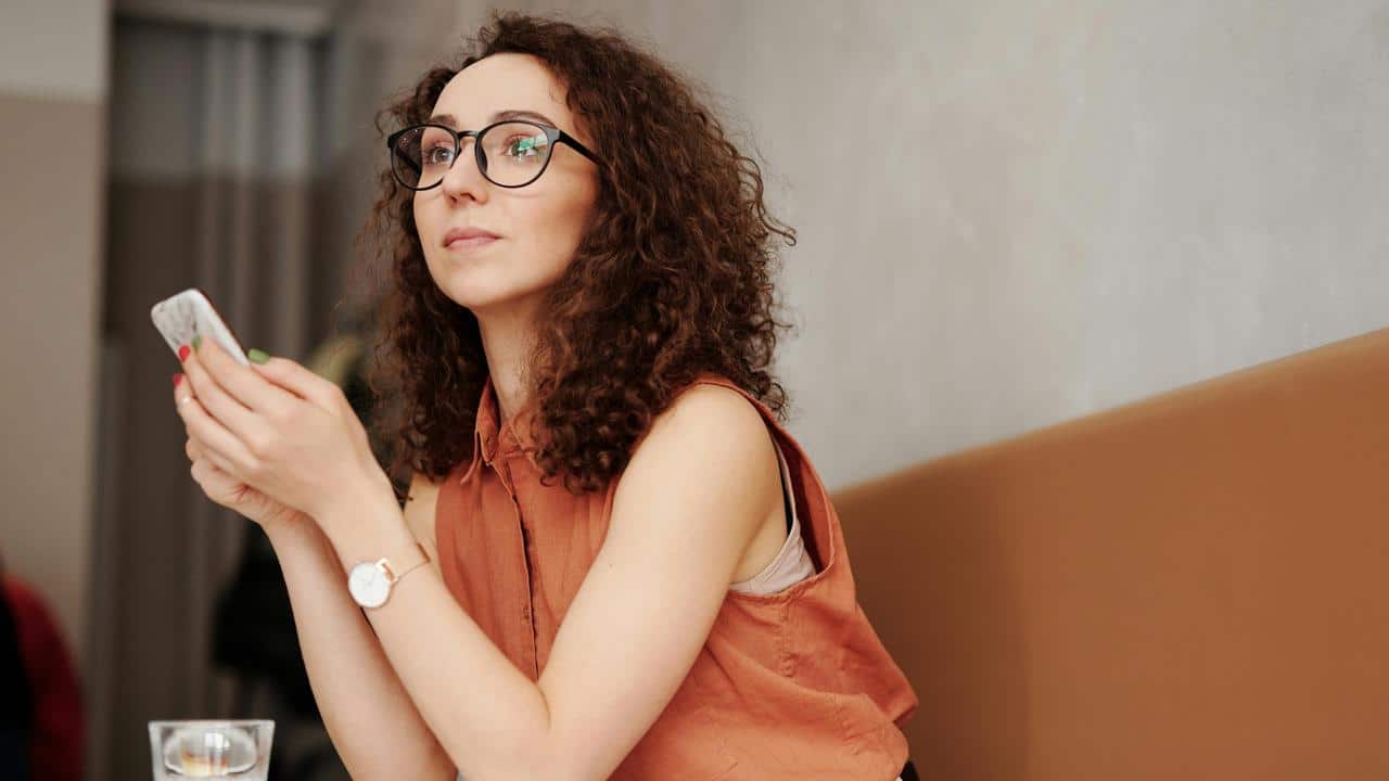 A person holding a smartphone while sitting at a table.