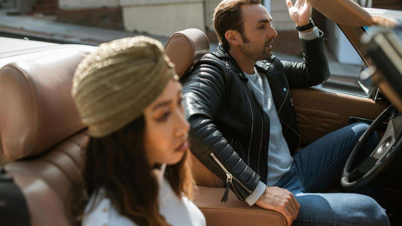 A couple sitting in a car looking upset and not speaking.