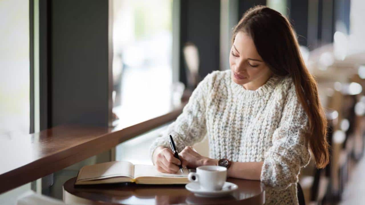 Woman journaling or reflecting alone at a coffee shop