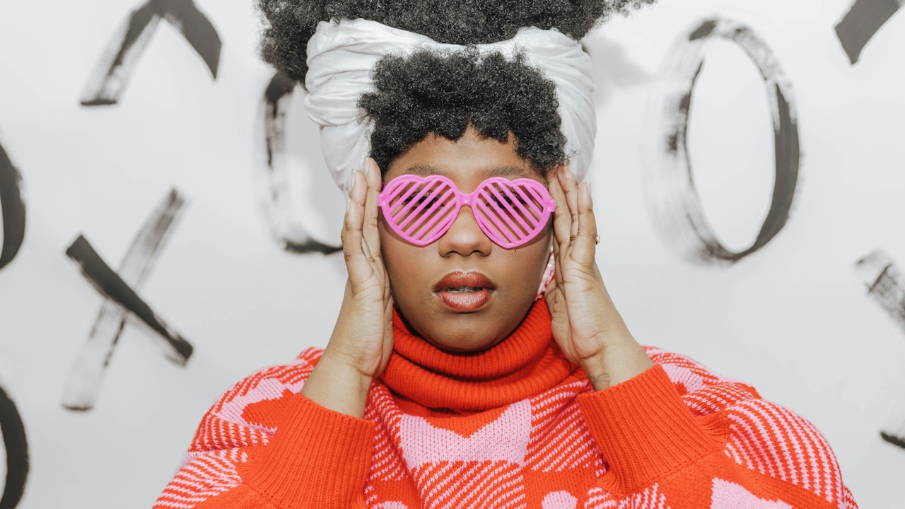 A woman with pink heart-shaped sunglasses covering her eyes.
