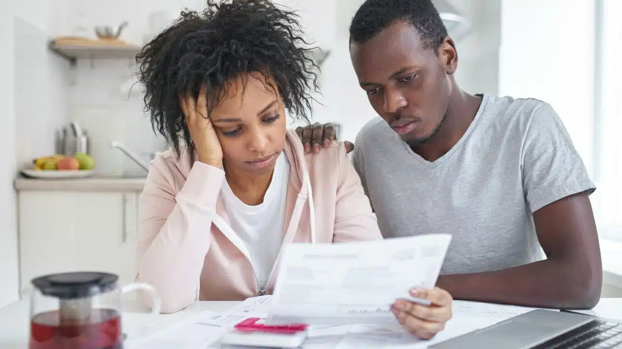 A man and woman sit at a table looking at a paper document together.