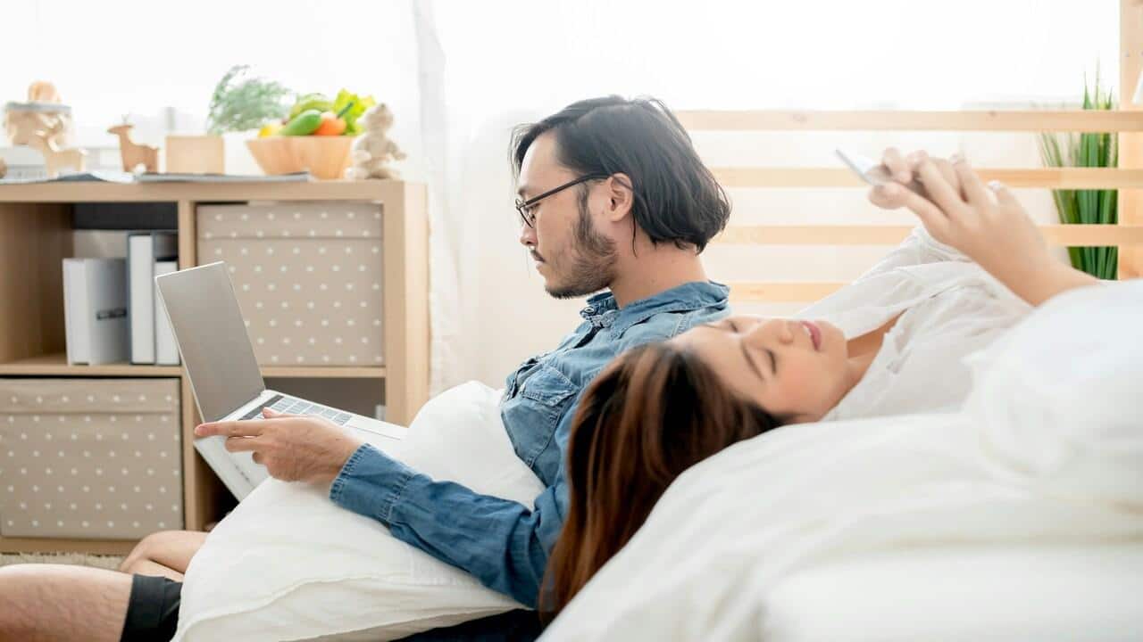 A couple busy with their devices at home